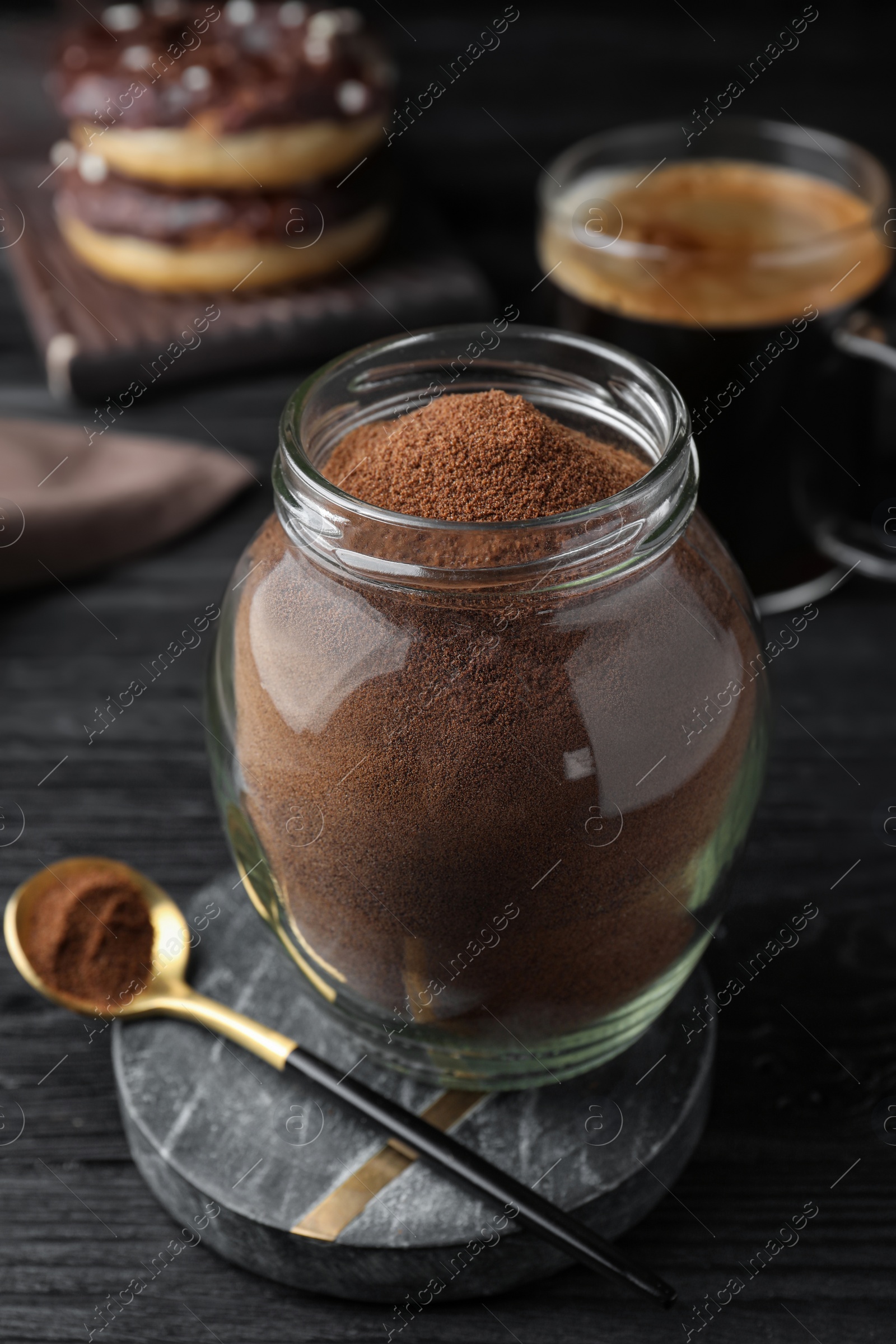 Photo of Jar of instant coffee and spoon on black wooden table