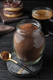 Jar of instant coffee and spoon on black wooden table