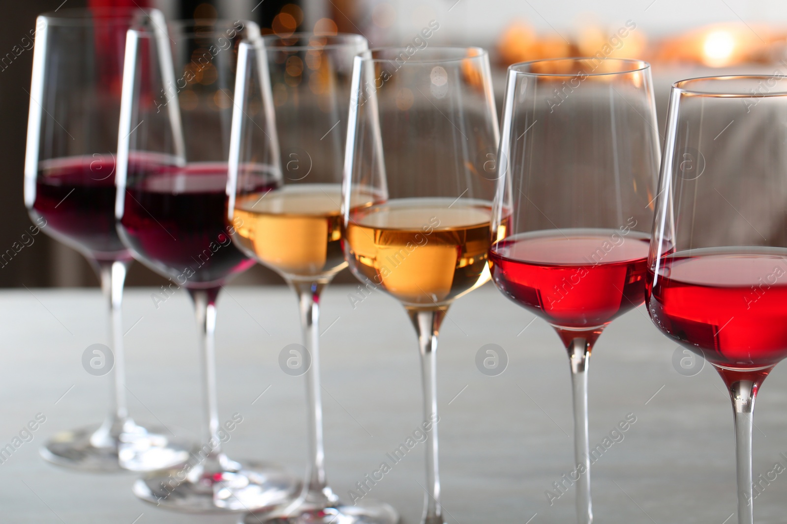 Photo of Row of glasses with different wines on table against blurred background, closeup