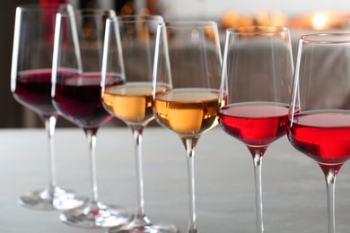 Photo of Row of glasses with different wines on table against blurred background, closeup