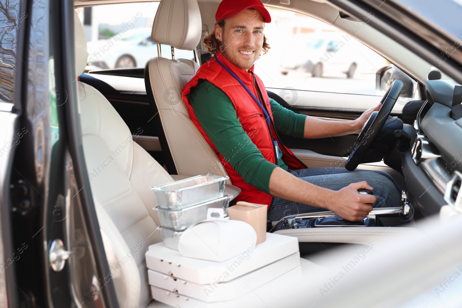 Photo of Male courier with orders in car. Food delivery service