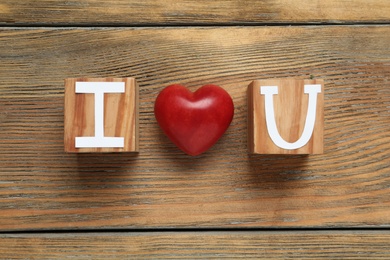 Photo of Phrase I Love You made of cubes with letters and heart on wooden table, flat lay