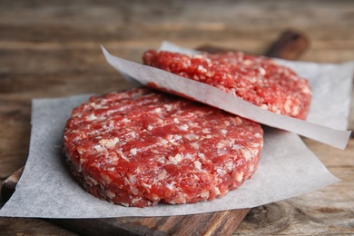 Raw meat cutlets for burger on wooden table, closeup