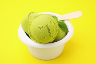 Tasty matcha ice cream in bowl on yellow background