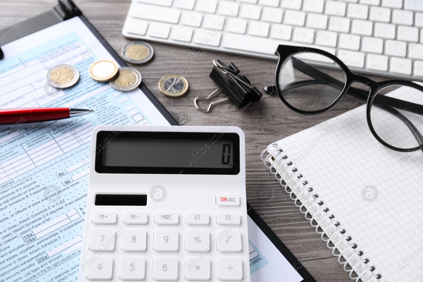 Photo of Tax accounting. Calculator, document, stationery and coins on wooden table, closeup