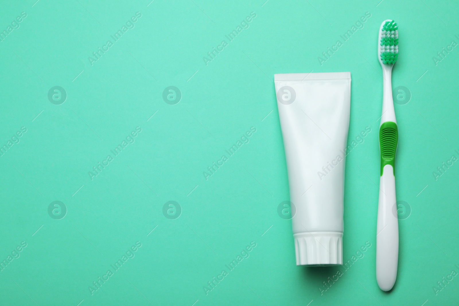 Photo of Blank tube of toothpaste and brush on color background, top view with space for text