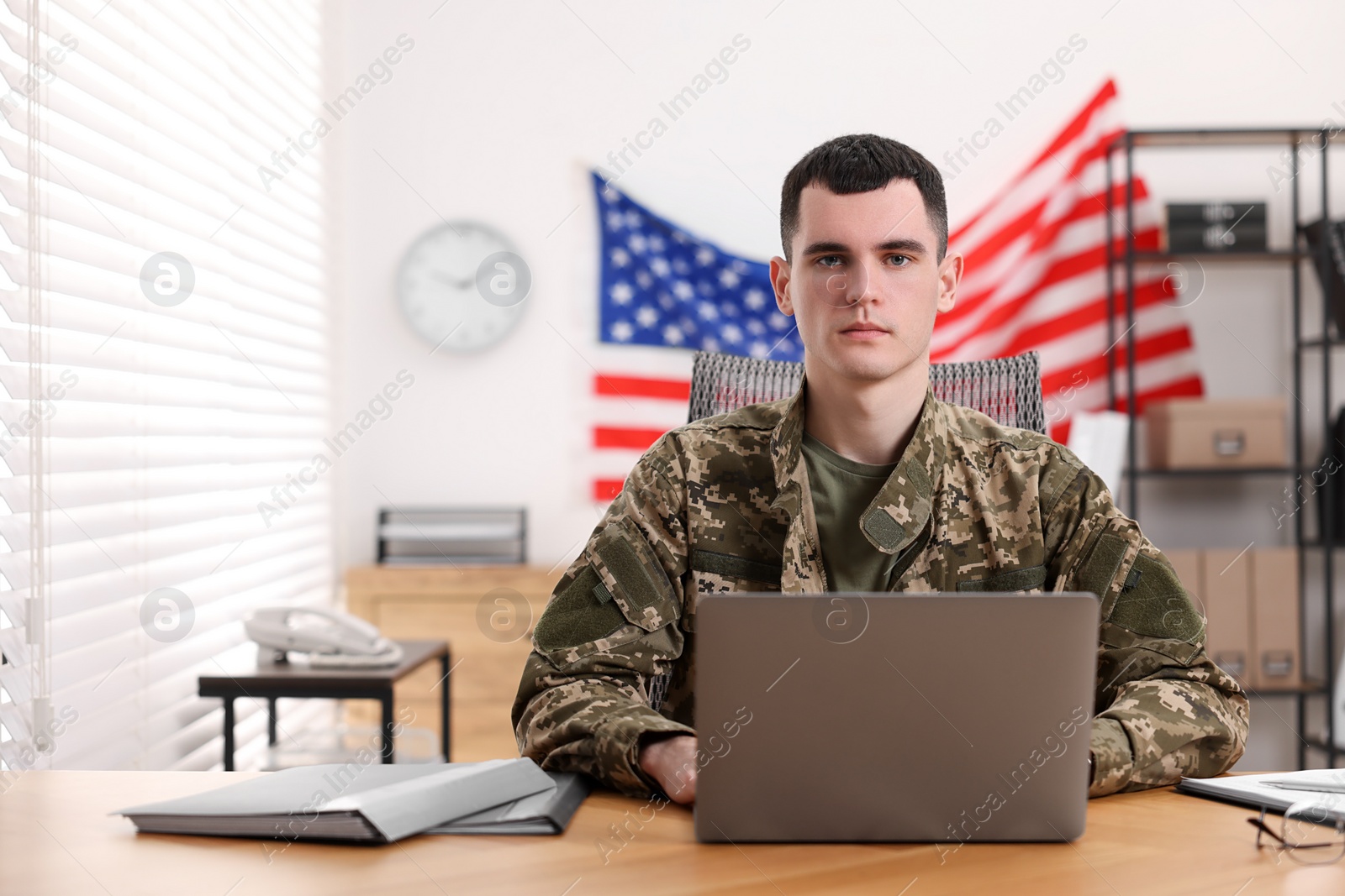 Photo of Military service. Young soldier working at table in office, space for text