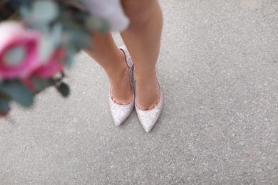 Young woman in elegant shoes walking on street