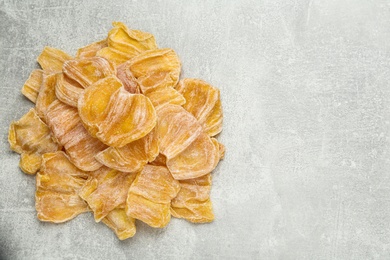 Photo of Delicious dried jackfruit slices on light grey table, flat lay. Space for text