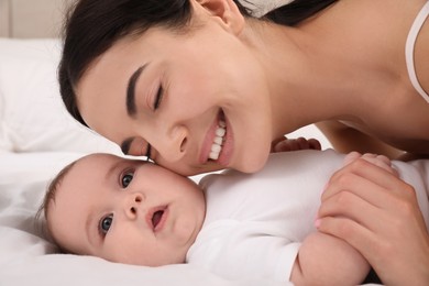 Photo of Young mother with her little baby on bed, closeup