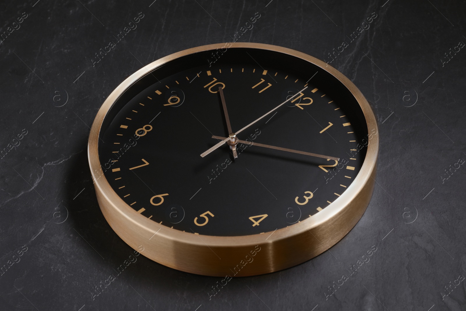 Photo of Stylish round clock on black table, closeup. Interior element