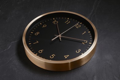 Photo of Stylish round clock on black table, closeup. Interior element