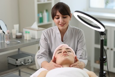 Photo of Cosmetologist making face massage to client in clinic