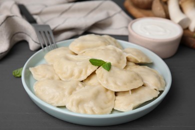 Photo of Plate of delicious dumplings (varenyky) on grey wooden table, closeup