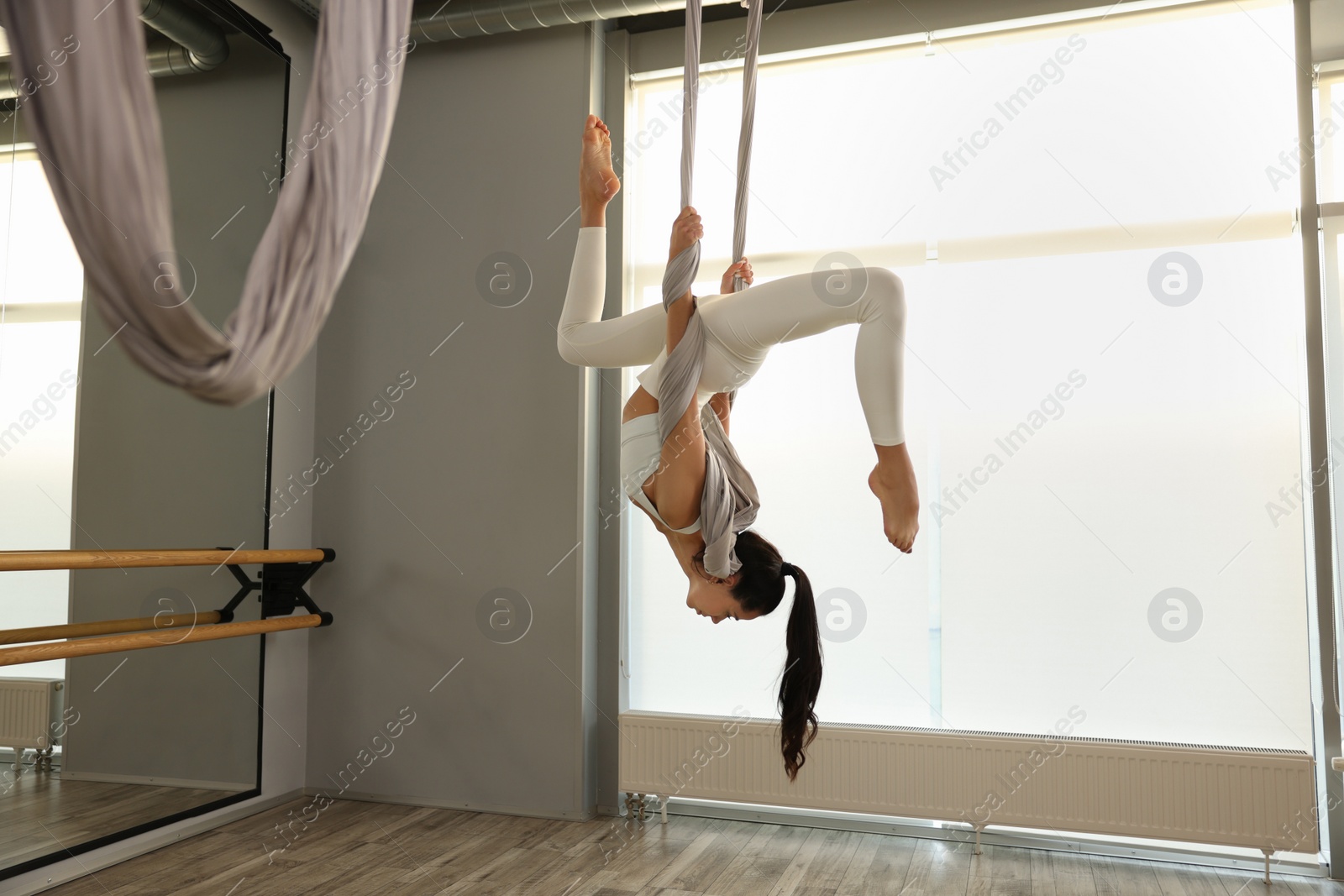 Photo of Young woman practicing fly yoga on hammock in studio