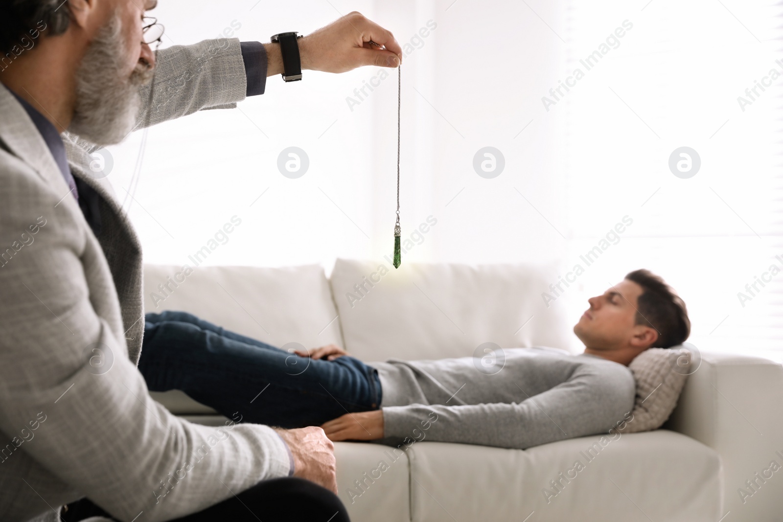 Photo of Psychotherapist using pendulum during hypnotherapy   session in office