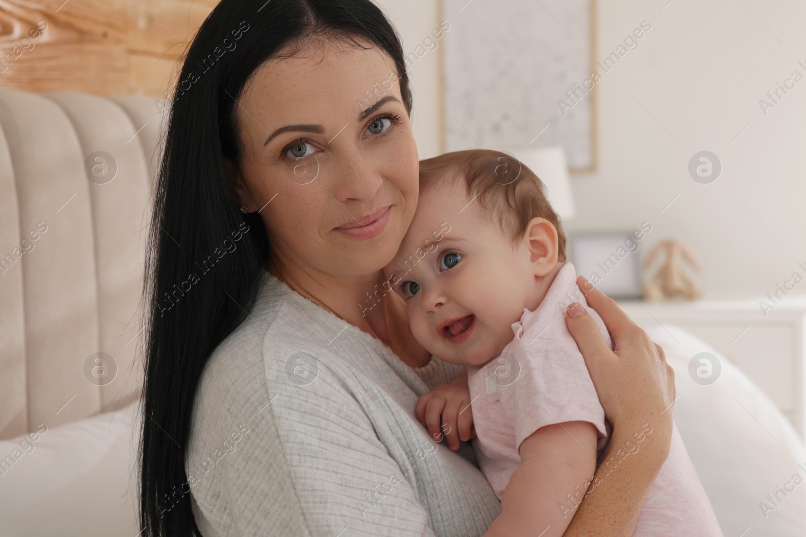 Photo of Happy woman with her little baby on bed at home