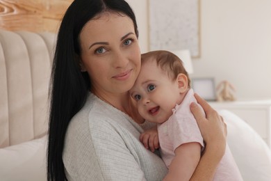 Happy woman with her little baby on bed at home