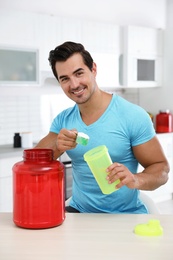 Young athletic man preparing protein shake in kitchen