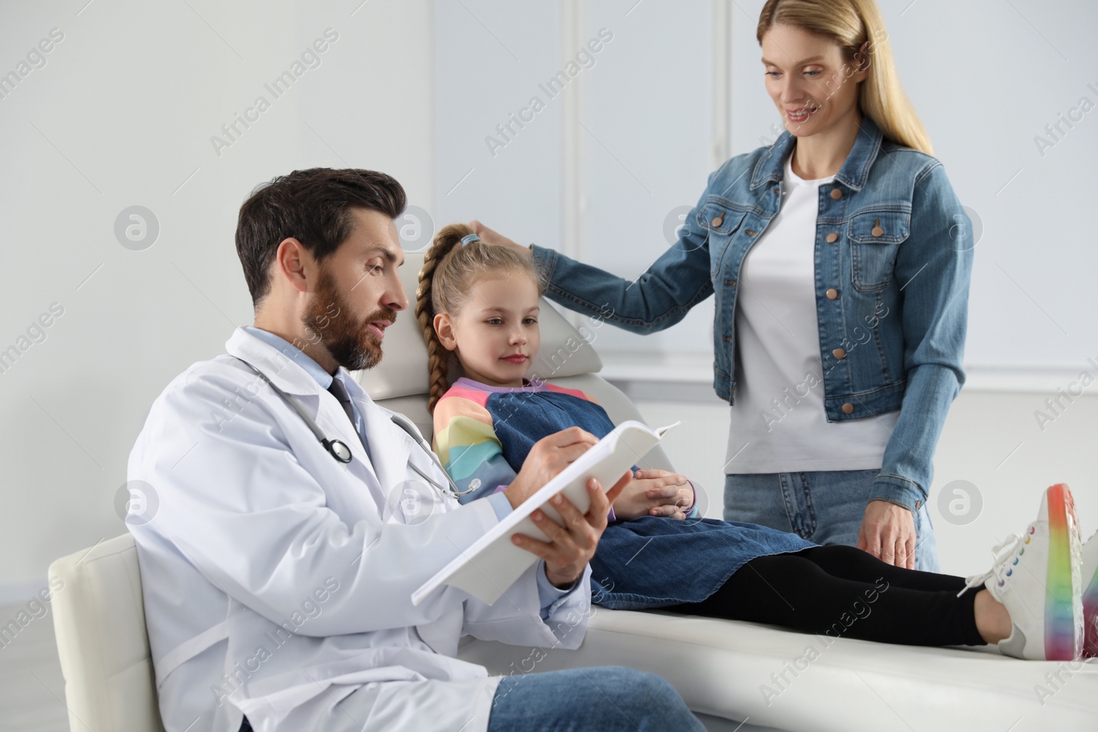 Photo of Mother and daughter having appointment with doctor. Pediatrician consulting patient in clinic