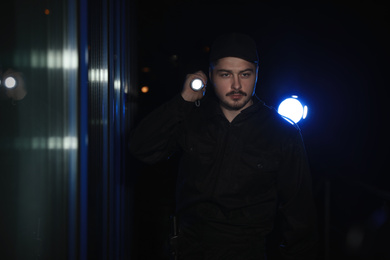 Photo of Male security guard with flashlight in dark corridor