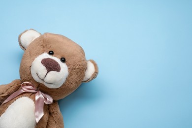 Photo of Cute teddy bear on light blue background, top view. Space for text