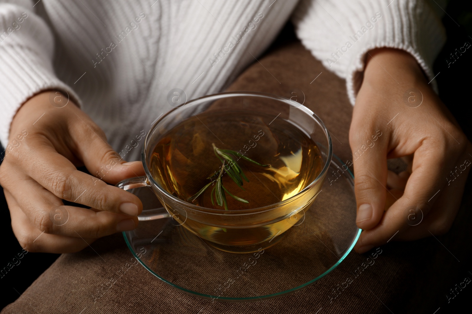 Photo of Woman drinking tasty herbal tea on sofa, closeup view