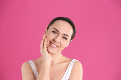 Portrait of beautiful mature woman on pink background