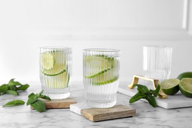 Glasses of lemonade with stylish cup coasters on marble table