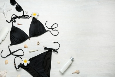 Photo of Flat lay composition with black swimsuit and beach accessories on light stone background. Space for text