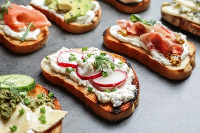 Photo of Many different tasty bruschettas on grey table