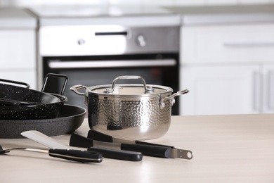 Set of clean cookware and utensils on table in kitchen. Space for text