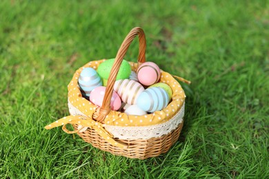 Photo of Easter celebration. Painted eggs in wicker basket on green grass