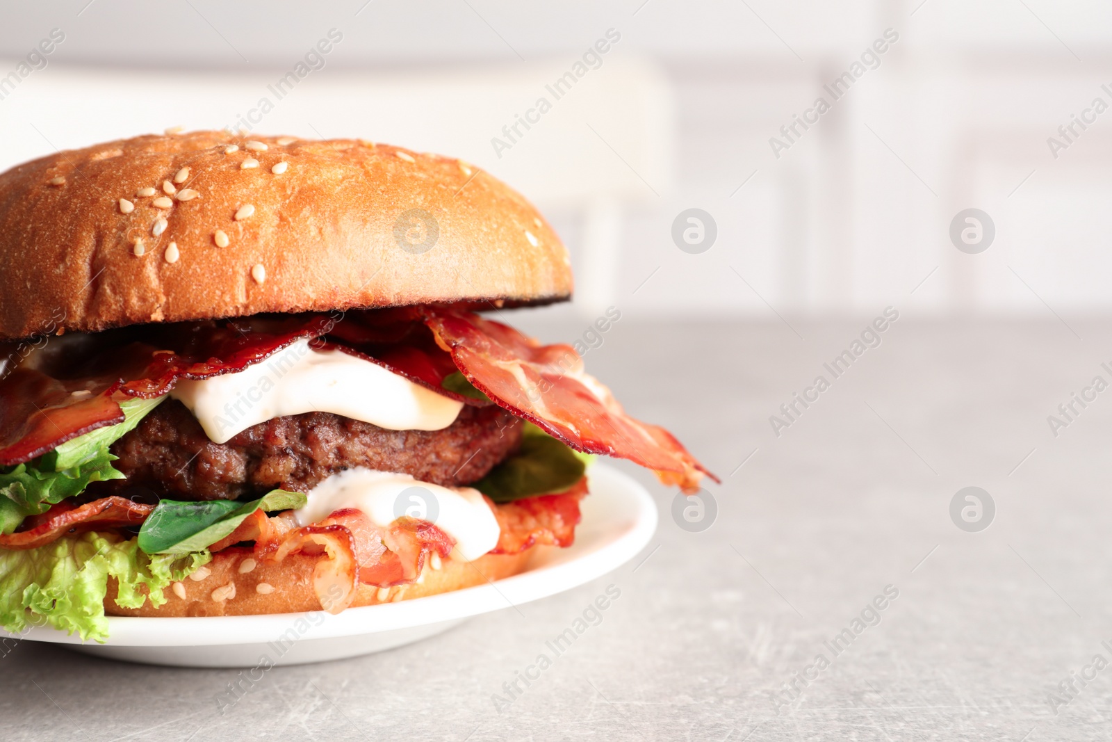 Photo of Plate with tasty bacon burger on table