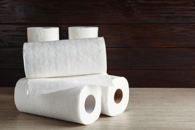 Photo of Many rolls of white paper towels on wooden table. Space for text