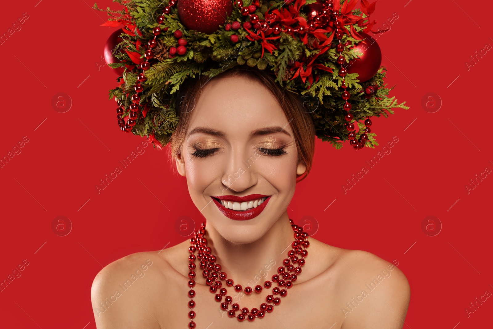 Photo of Beautiful young woman wearing Christmas wreath on red background