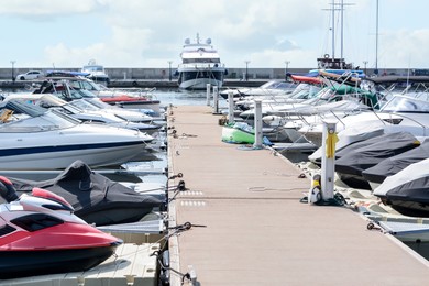 Photo of Beautiful view of city pier with moored boats and water scooters on sunny day
