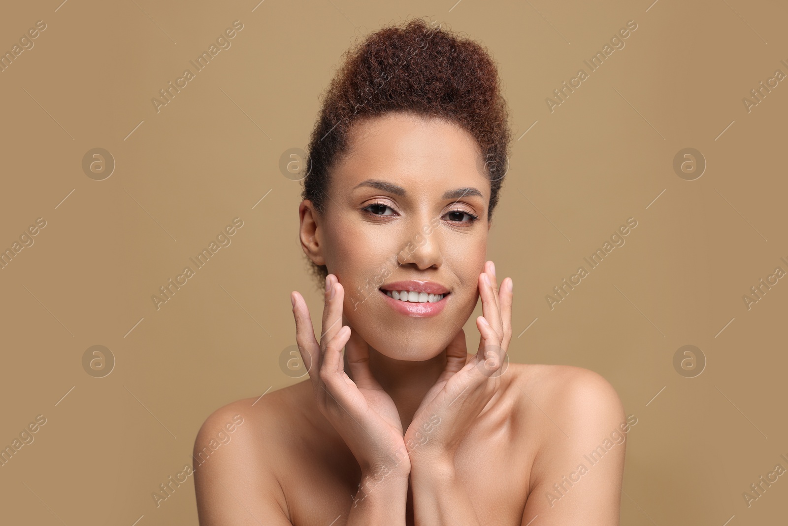 Photo of Portrait of beautiful young woman with glamorous makeup on light brown background