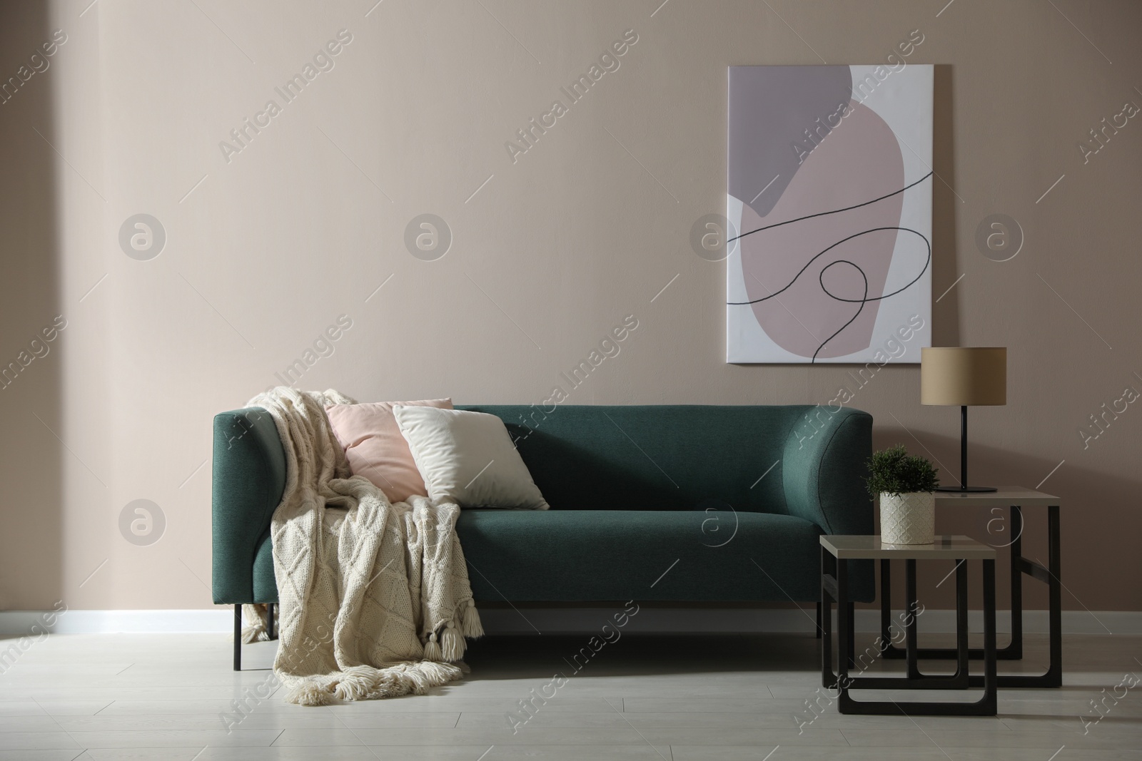 Photo of Stylish living room interior with comfortable green sofa and beautiful painting