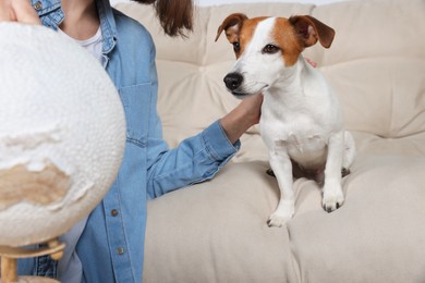 Woman with globe near dog indoors, closeup. Travel with pet concept