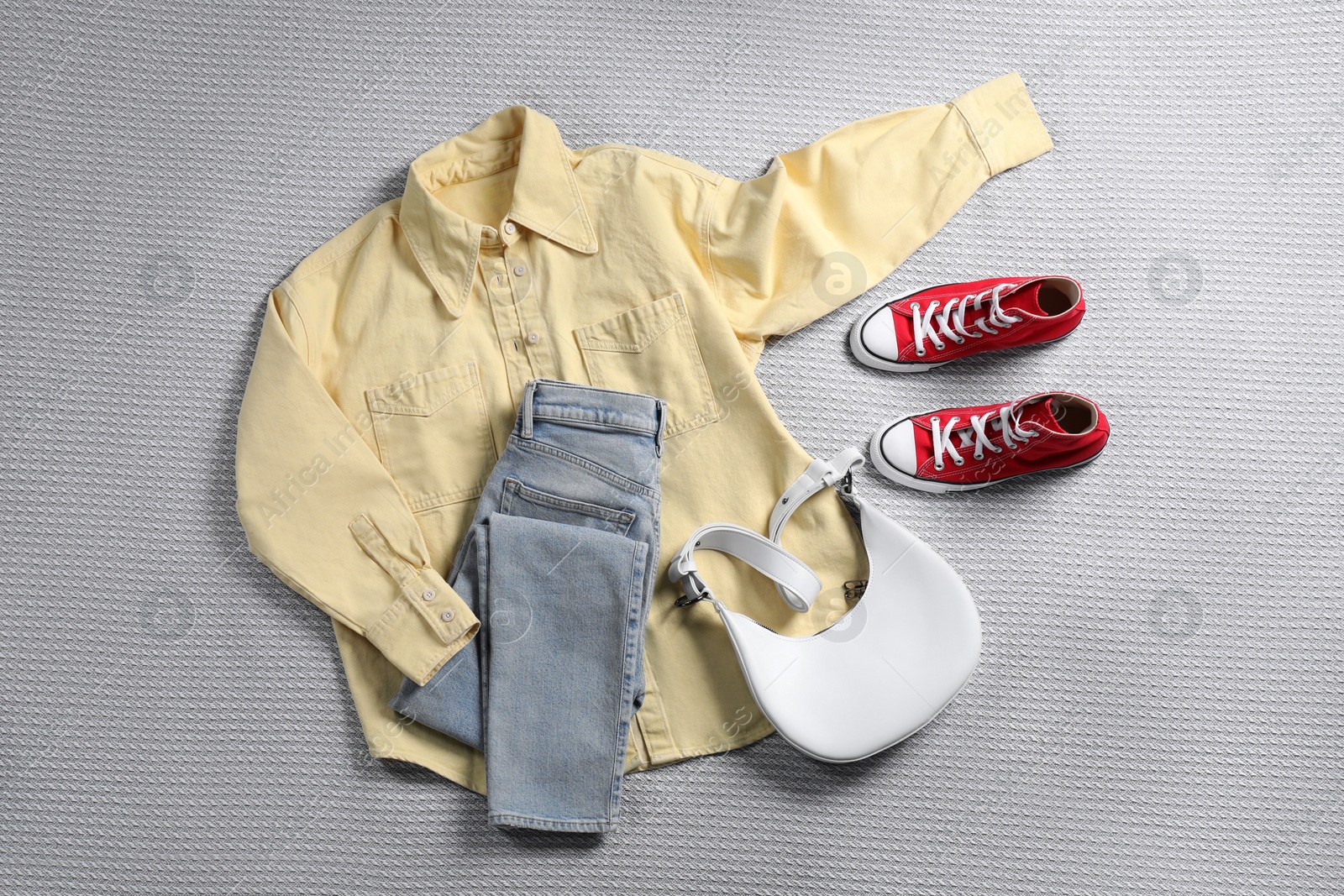 Photo of Pair of stylish red sneakers, clothes and bag on light grey fabric, flat lay