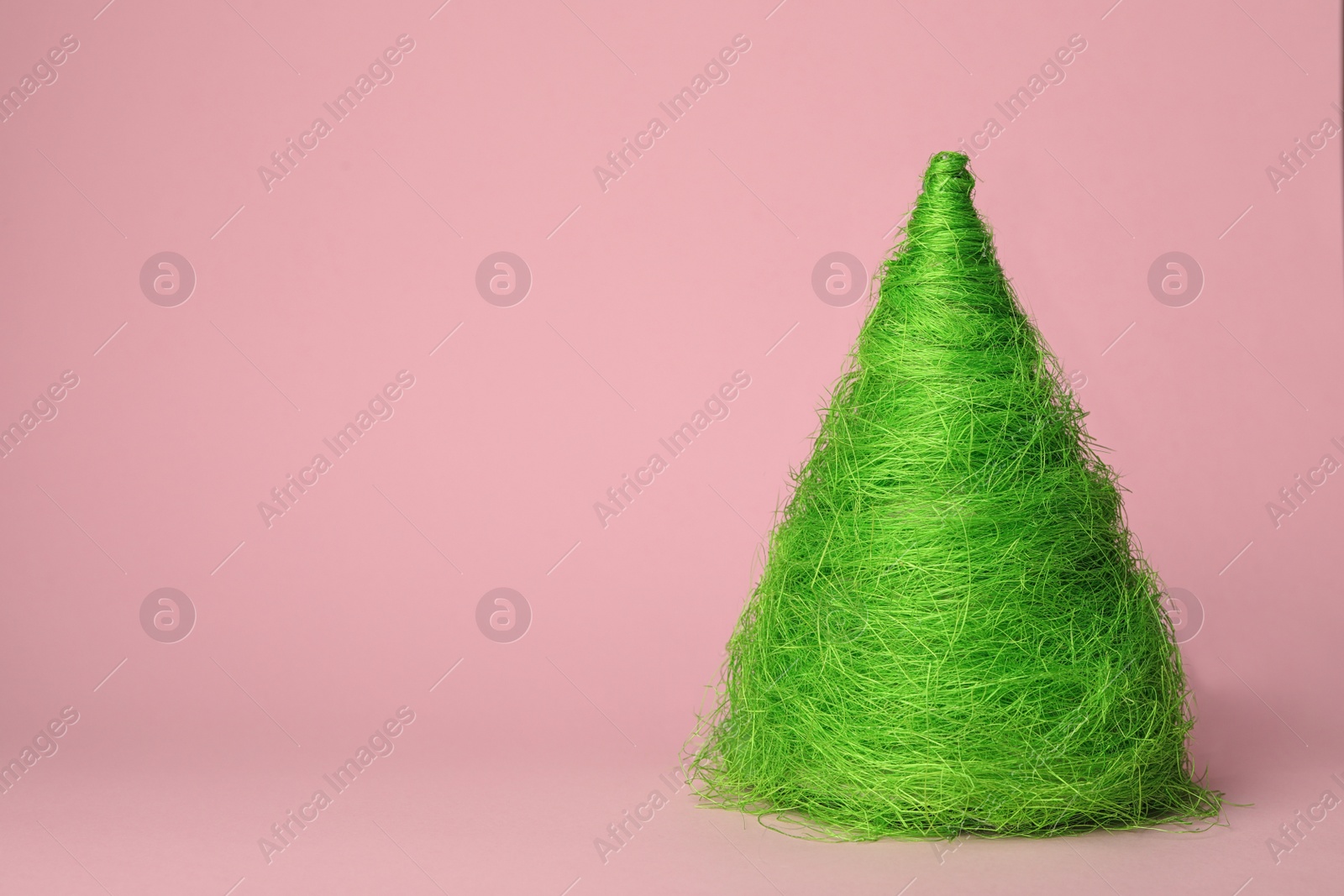 Photo of Christmas tree made of green threads on pink background, space for text