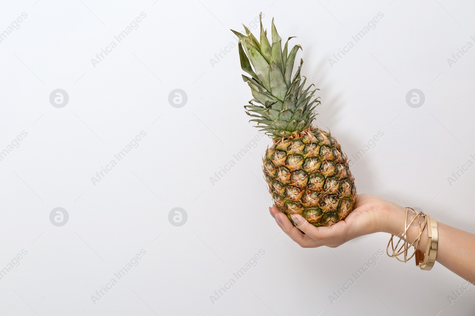 Photo of Woman holding pineapple on light background, closeup