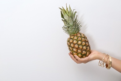 Photo of Woman holding pineapple on light background, closeup