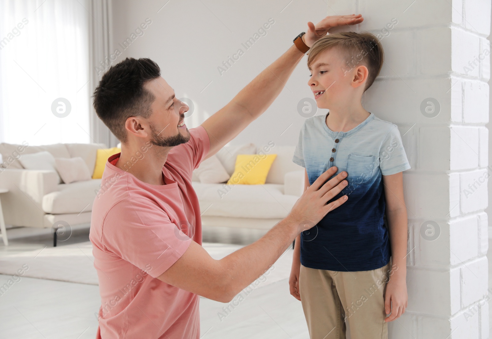 Photo of Father measuring height of his son near wall at home