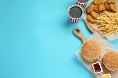 Photo of Different fast food on turquoise background, flat lay. Space for text