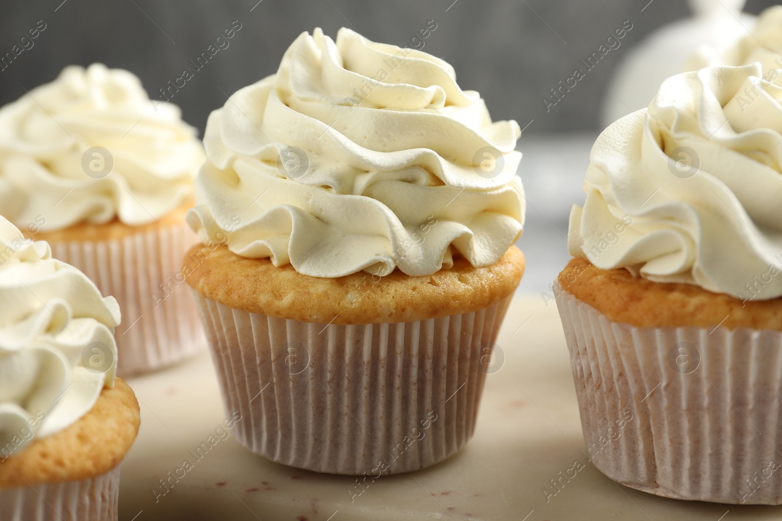 Photo of Tasty cupcakes with vanilla cream on table, closeup