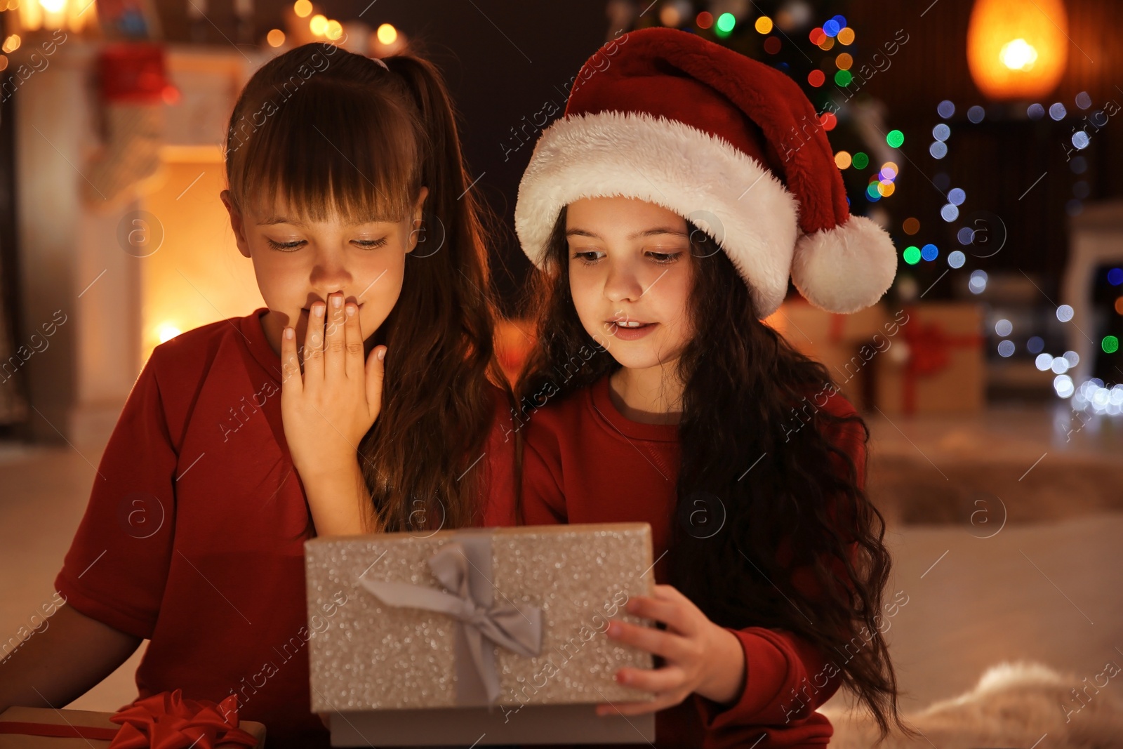 Photo of Cute little children with Christmas gift box at home