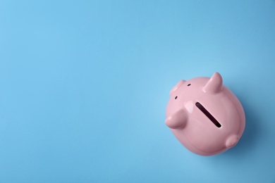 Pink piggy bank on color background, top view