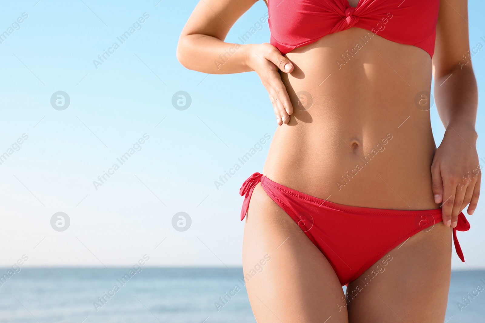 Photo of Young woman with sexy body wearing bikini on beach, closeup. Space for text